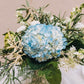 A delightful blend of blue and white blossoms graces a footed vase with an antique finish, exuding timeless charm. Named for a vibrant northwest Georgia city renowned for its pivotal role in the Civil War.