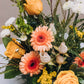 A vibrant medley of buttery yellow, rich peach, and crisp white blossoms bursts with life in a charming scalloped vase. Named for a quaint south Georgia town renowned for its Old South Day food, arts and crafts festival.