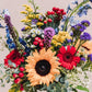 Pronounced "vy-anna," this arrangement bursts with a vibrant medley of sunny yellow, fiery red, deep blue, and regal purple blooms, all artfully composed in a sleek vase that reimagines the timeless double-handled urn. Inspired by a quaint south-central Georgia city renowned for its legendary BIG PIG JIG barbecue championship.