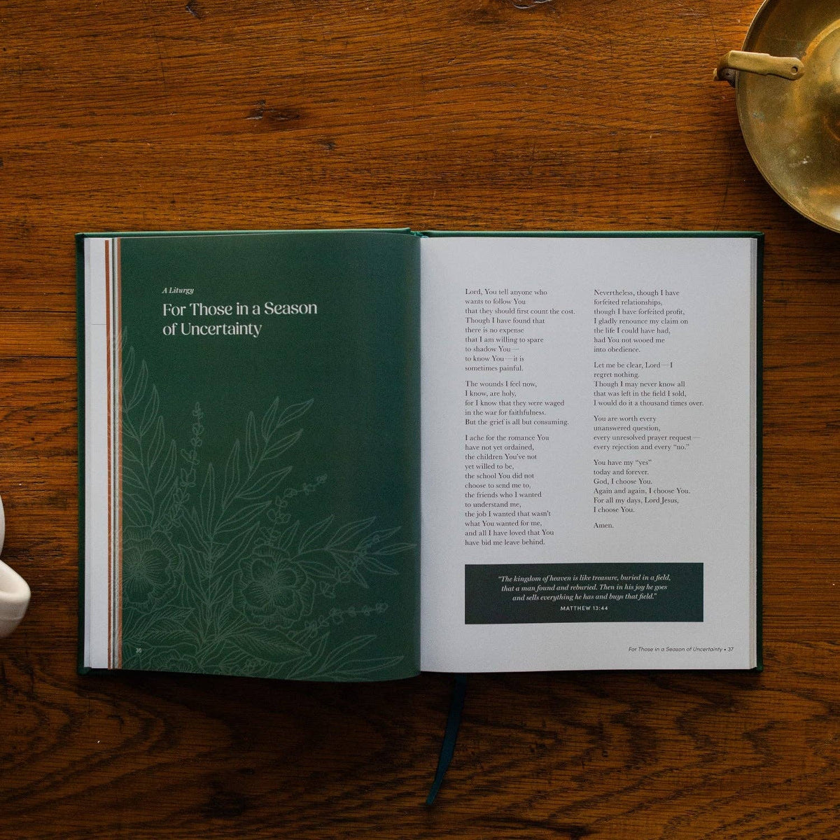 Deep green and white interior pages of "Draw Near to God" prayer book open on wood surface, showing botanical motif and prayer text with scripture quote.