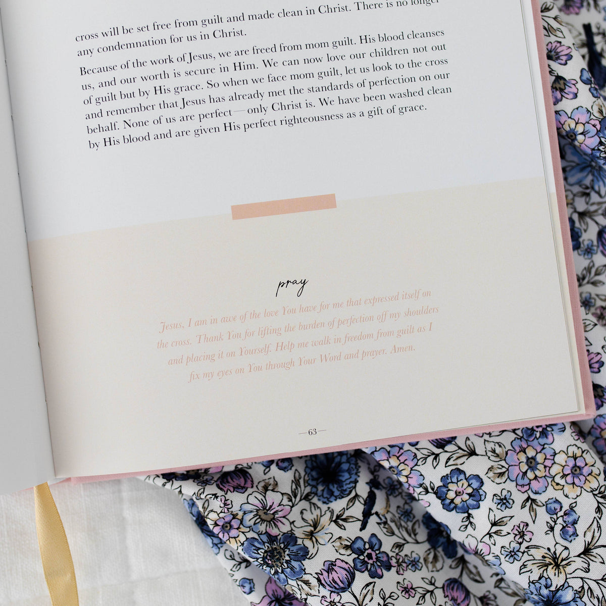 Open Motherhood Devotional page with "pray" section heading displayed on floral fabric