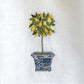 White linen kitchen towel with embroidered lemon topiary in yellow and green, set in a blue decorative pot.