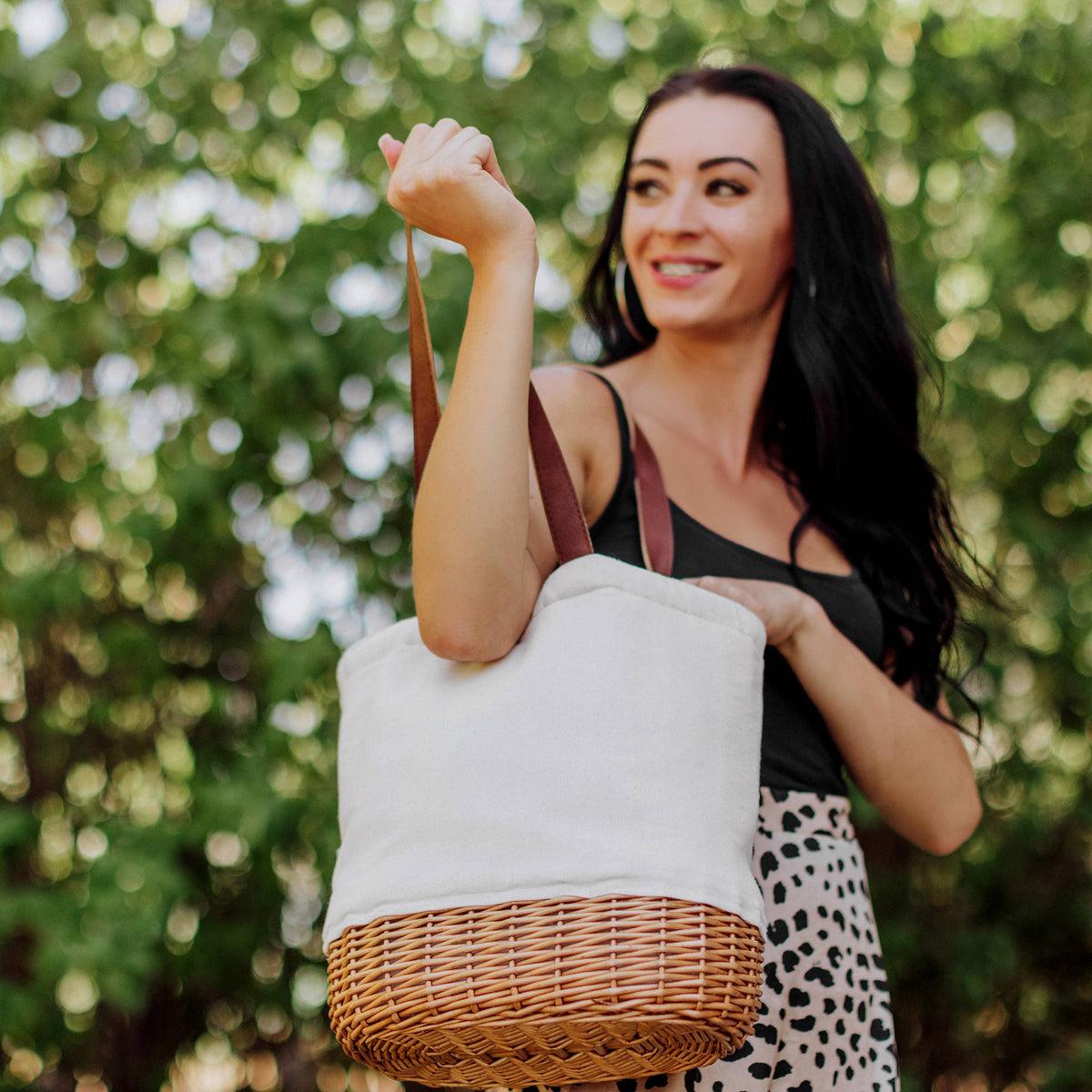 Cream canvas and woven willow Pico insulated basket tote with burgundy leather handles, held outdoors