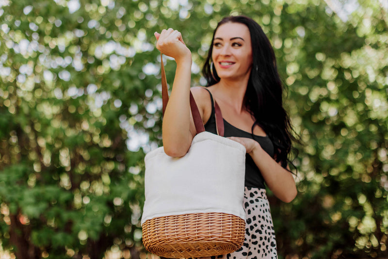 Cream canvas and woven willow Pico insulated basket tote with burgundy leather handles, held outdoors