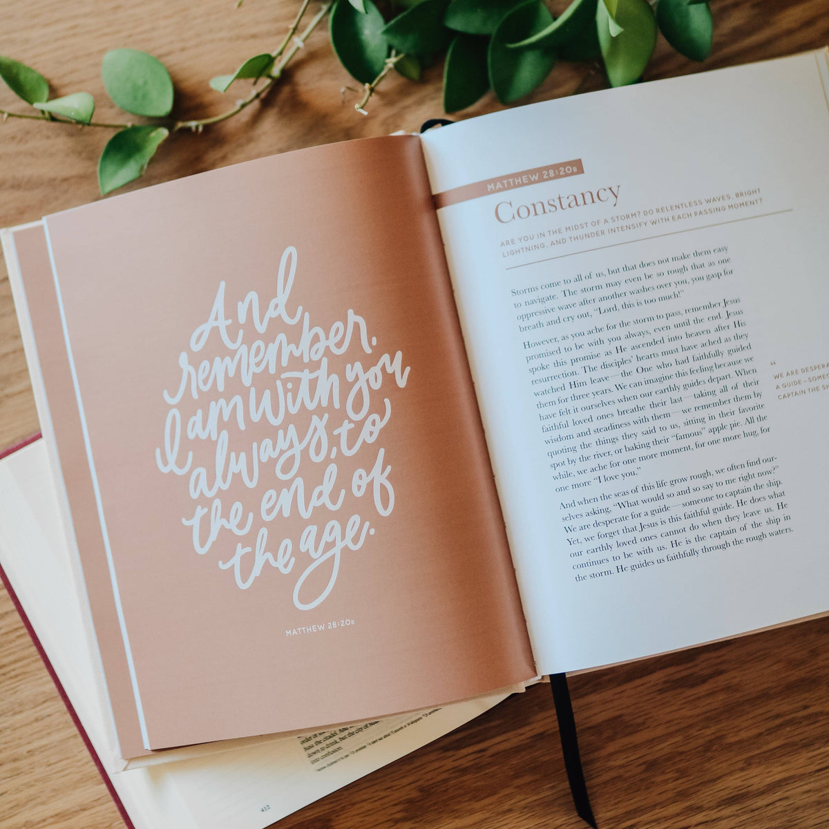 Open book with tan page displaying white script quote "And remember, I am with you always to the end of the age" beside chapter text on wooden surface.