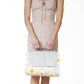 Picnic blanket in cream with yellow daisy pattern and quilted texture, held up by person in beige polka-dot dress