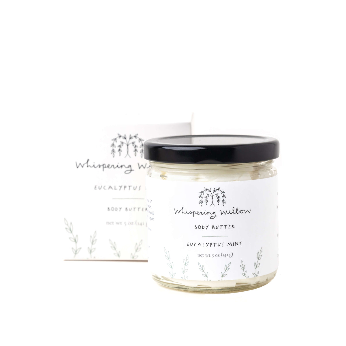 Whispering Willow Eucalyptus Mint body butter in clear glass jar with black lid, cream-colored formula, labeled with delicate eucalyptus branch illustration