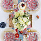 Floral Wave paper plates in red and white set with natural placemats, gold flatware, white hydrangeas, and patriotic table styling for an outdoor gathering.