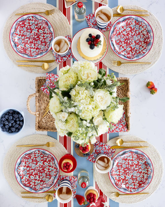 Floral Wave paper plates in red and white set with natural placemats, gold flatware, white hydrangeas, and patriotic table styling for an outdoor gathering.