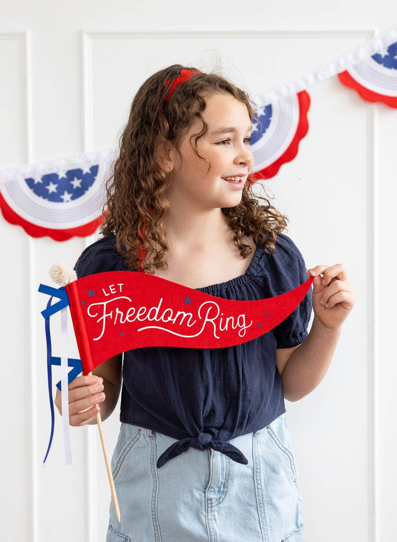 Red felt pennant banner with "Let Freedom Ring" script and stars, displayed against patriotic bunting