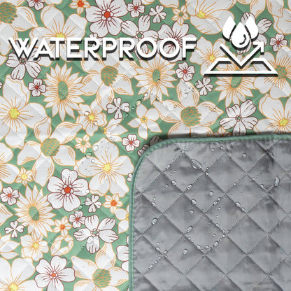 Floral picnic blanket with daisy pattern on green ground; waterproof gray quilted backing shown with water beads, demonstrating moisture resistance.
