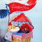 Red felt pennant banner reading "Let Freedom Ring" with white script lettering, displayed above patriotic blue and red decorative bunting.