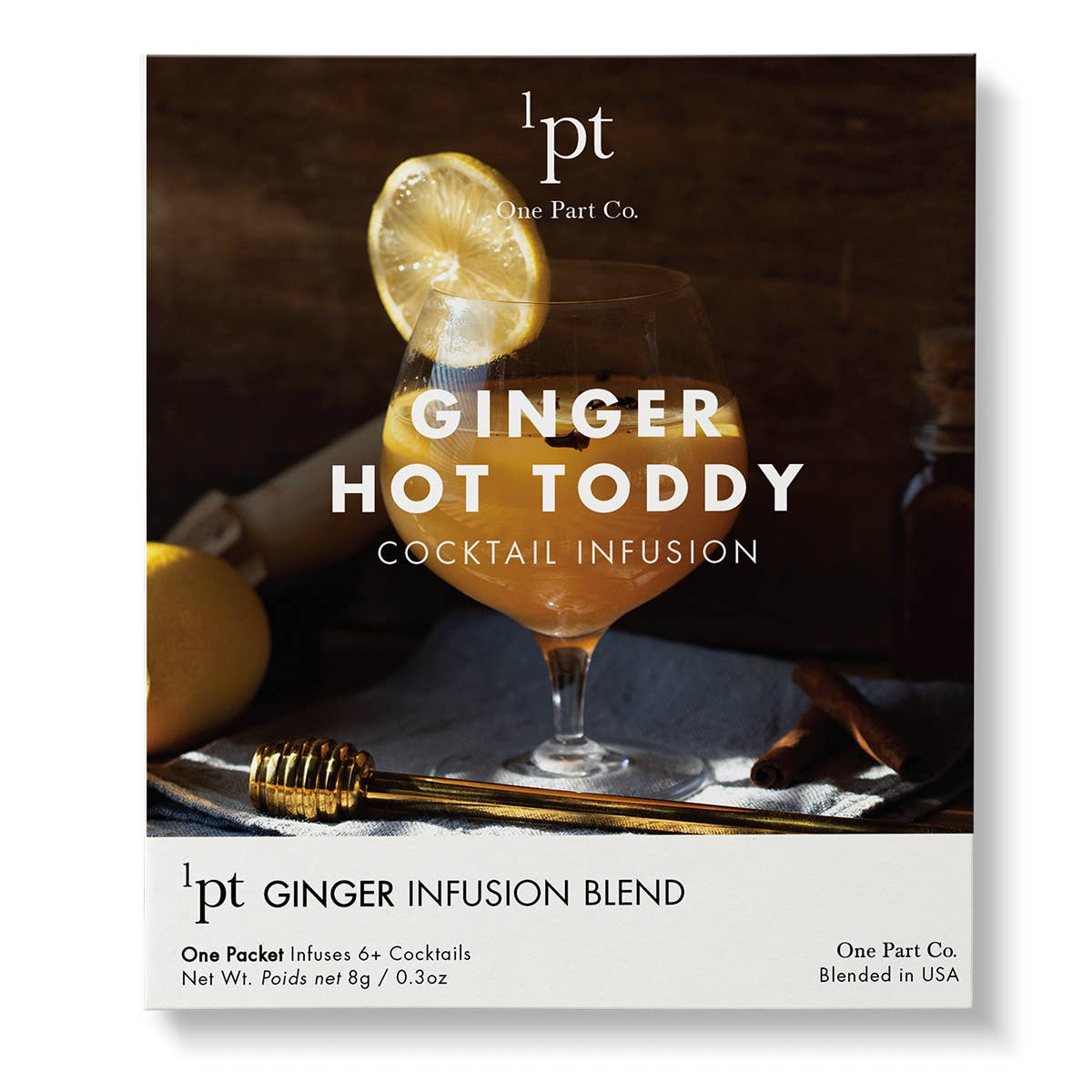 Golden ginger hot toddy cocktail in a coupe glass, garnished with lemon slice and gold honey stick stirrer