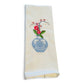 White cotton dish towel with embroidered red flowers in decorative blue vase and green leaves