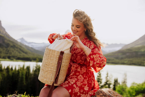 Beige handwoven rush tote with brown leather shoulder strap, displayed open with cream lining