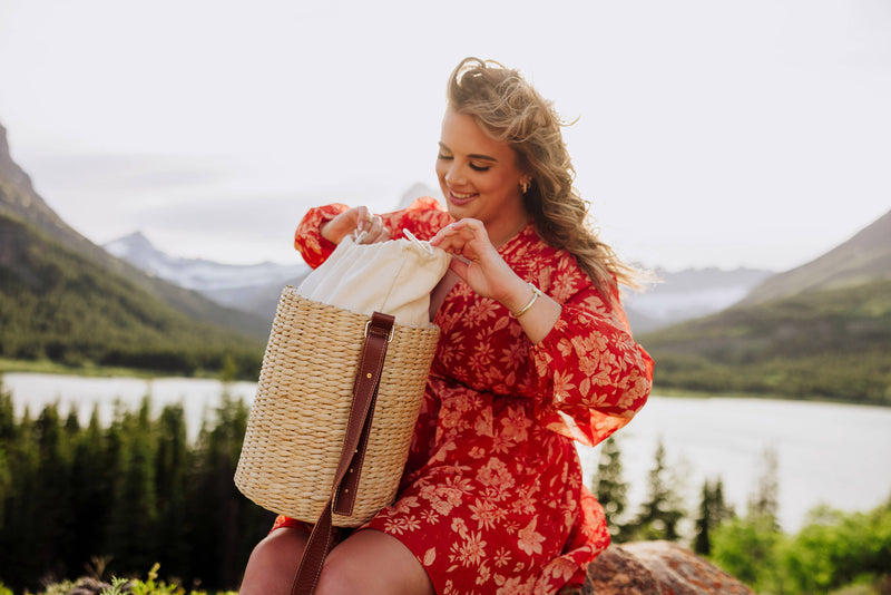 Beige handwoven rush tote with brown leather shoulder strap, displayed open with cream lining