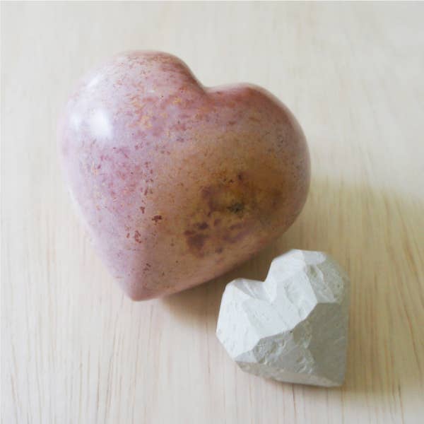 Large hand-carved soapstone heart in mauve with natural stone texture, displayed next to white soapstone heart for size reference