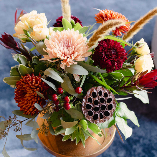 Colorful floral arrangement with a wooden bowl on a blue background