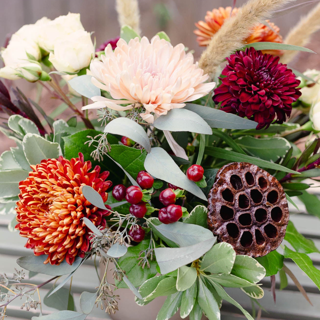 Colorful floral arrangement with various flowers and greenery on a wooden surface