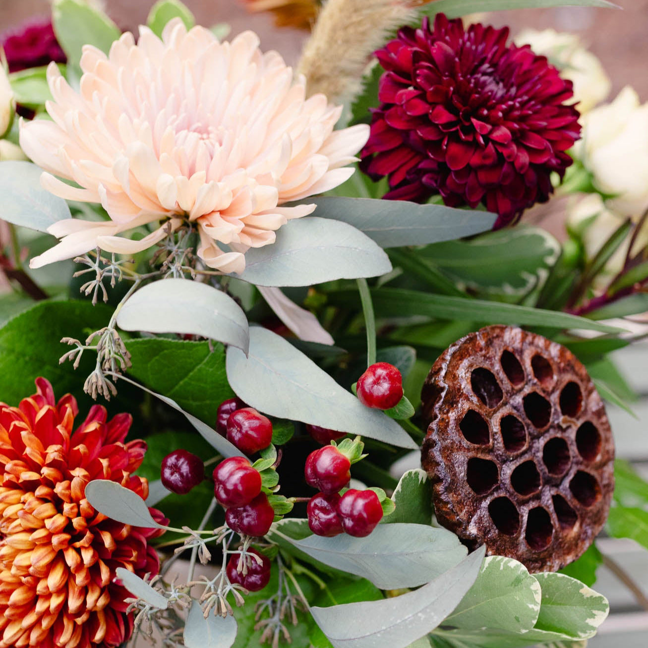Colorful floral arrangement with large flowers and greenery on a blurred background