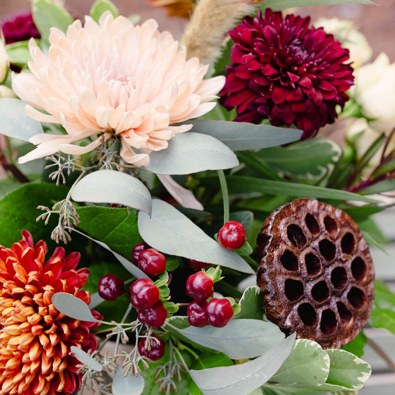 Colorful floral arrangement with large flowers and greenery on a blurred background