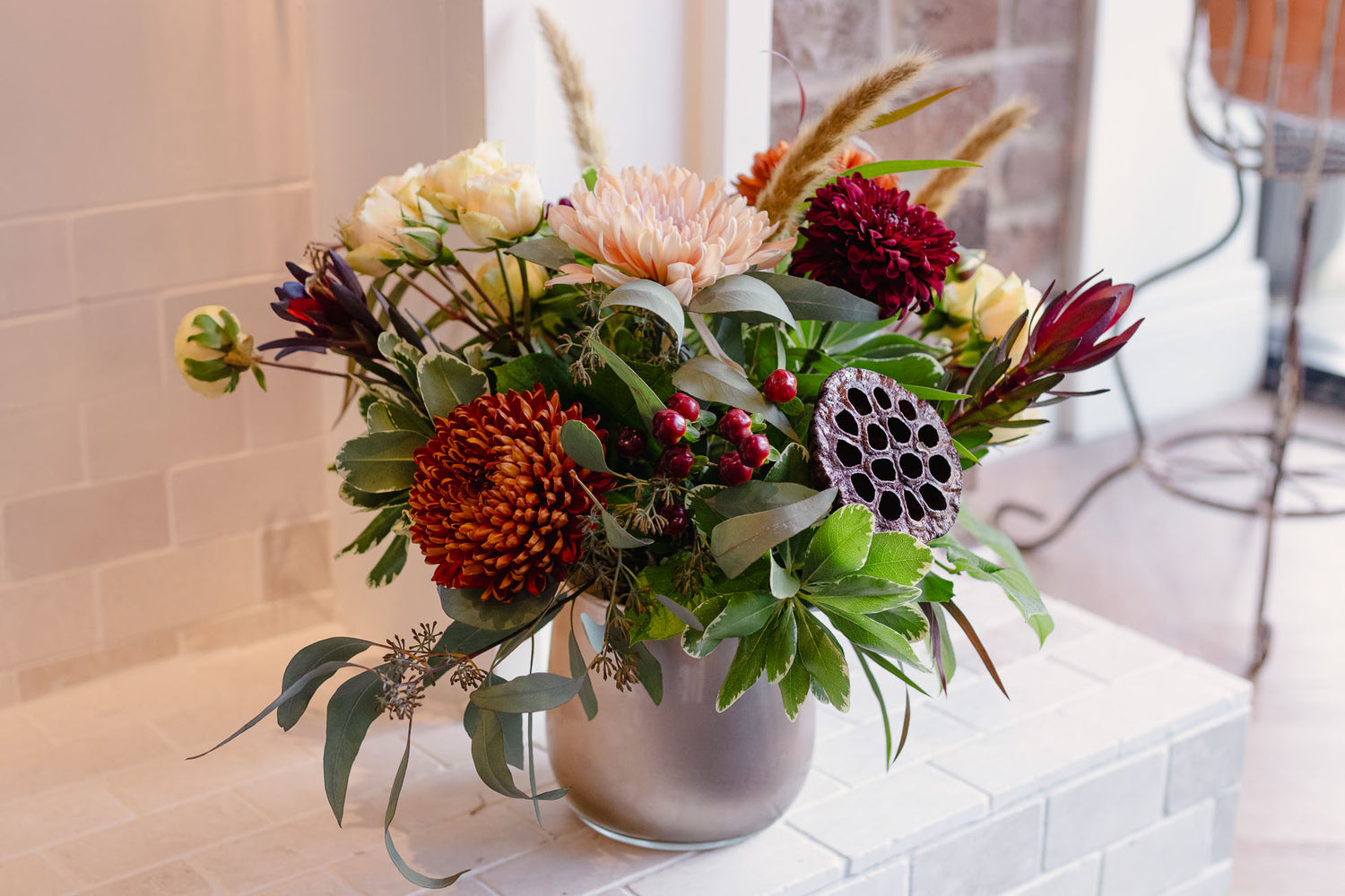Bouquet of flowers in a silver vase on a tiled surface