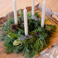 Decorative arrangement with candles and greenery on a wooden surface