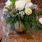 Floral arrangement on a wooden table with glasses and cutlery