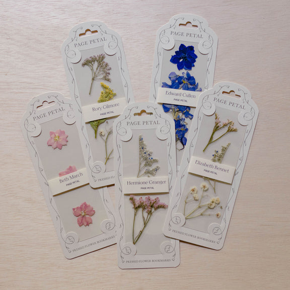 Five Page Petal floral bookmarks with pressed flowers—pink blossoms, blue petals, yellow botanical, delicate green herbs, and brown foliage—on cream cardstock with decorated headers.
