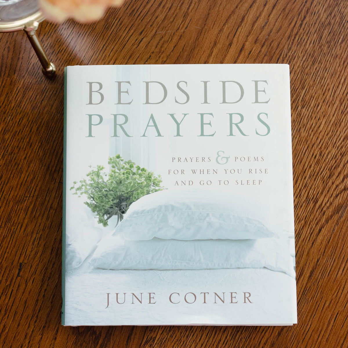 Bedside Prayers by June Cotner book on wood surface with yellow flower and pillow styling