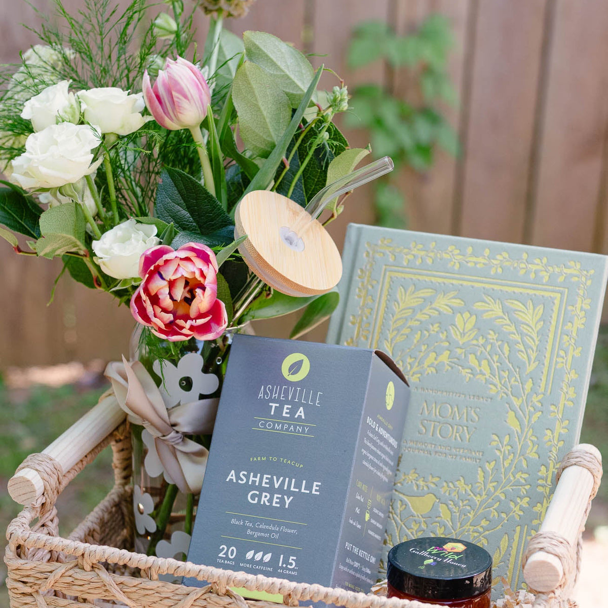 Wicker basket with flowers, candles, and books on a blurred outdoor background