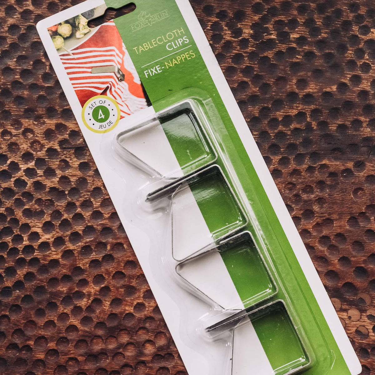 Set of 4 silver tablecloth clips with metal clamps, displayed on packaging with green branding